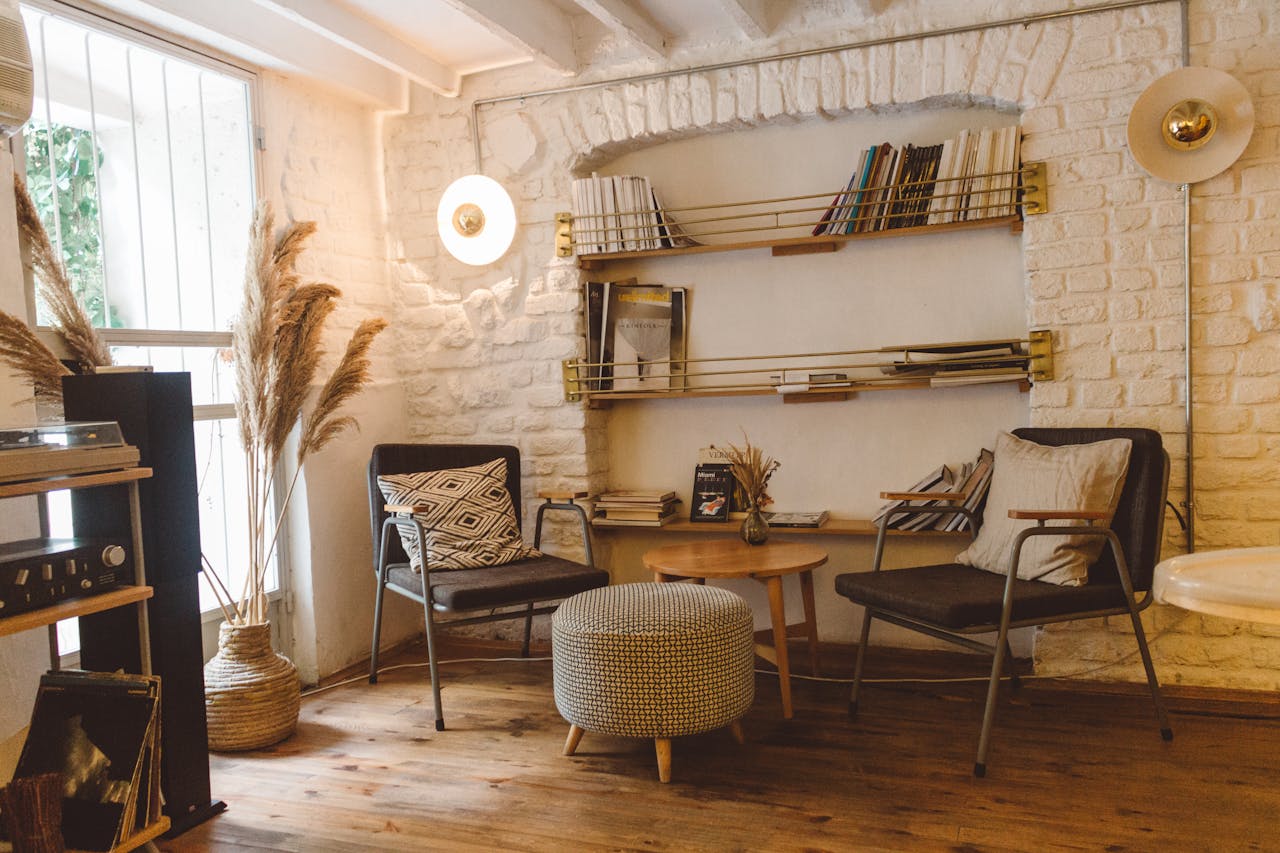 story-img Inviting modern rustic living room featuring armchairs, an ottoman, and a stylish bookshelf.